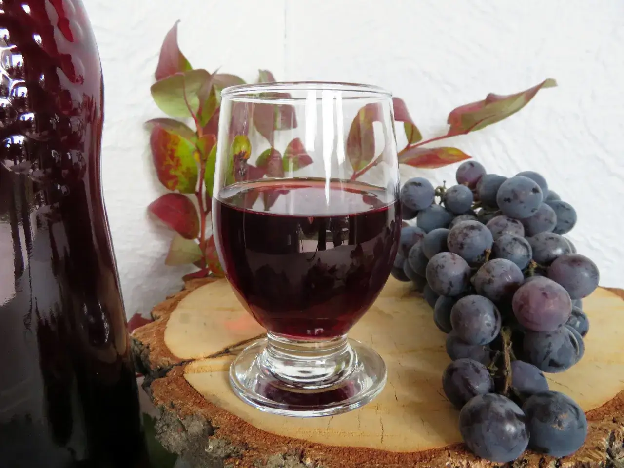 Szklanka wina, kiść winogron i butelka - idealne składniki na przepis na wino z winogron 10l.
