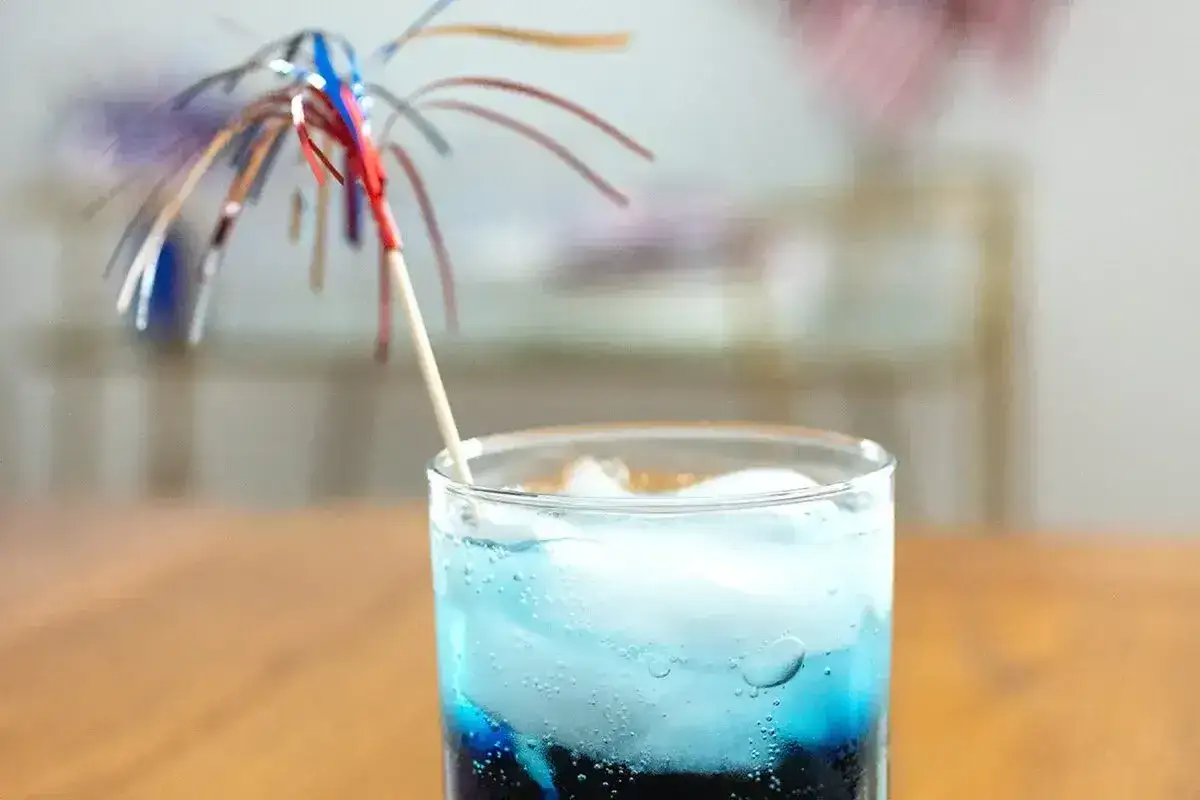 Niebieski drink z lodem i parasolką. Idealny na letnie popołudnie, gdy szukasz przepisu na blue curacao.