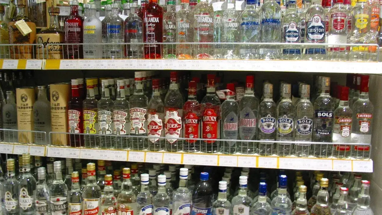 Półki sklepowe uginają się pod ciężarem butelek z wódką, tworząc wizualizację listy top 10 wódek w Polsce.