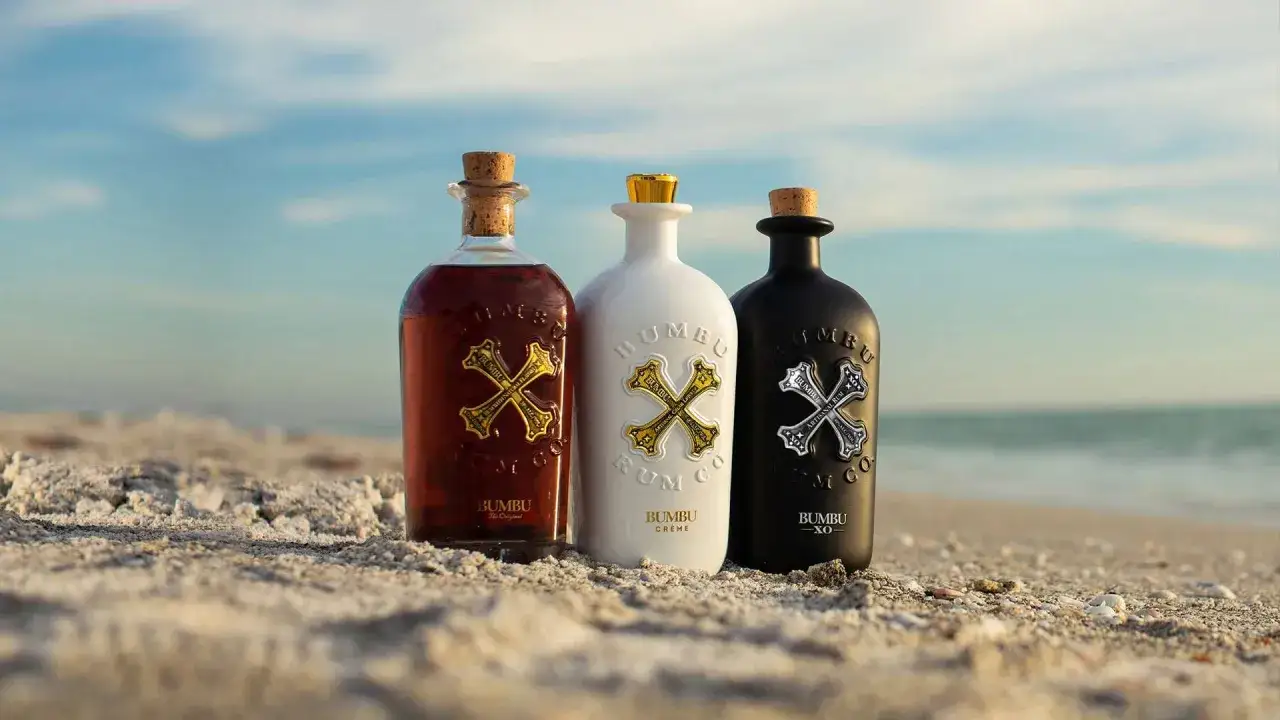 Trzy butelki Bumbu Rum na plaży. Jak pić ten rum? Ciesz się nim solo lub z lodem.