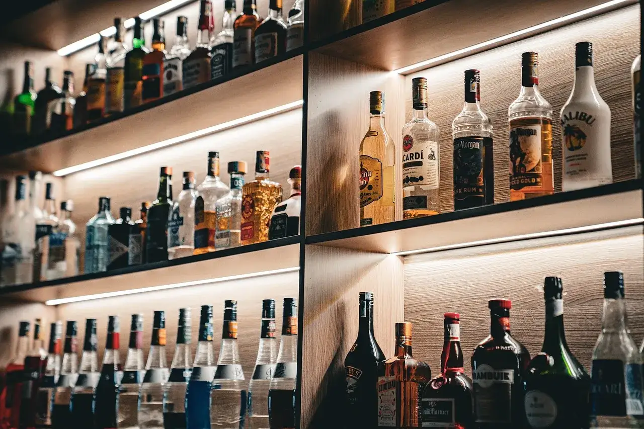 Na półkach widać różne rodzaje whisky i inne alkohole, od jasnych po ciemne, gotowe do degustacji.