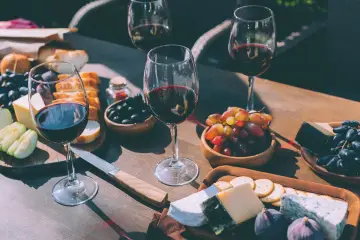 Degustacja merlot: jakie to wino? Kieliszki czerwonego wina, sery, winogrona, oliwki i pieczywo tworzą idealną kompozycję.