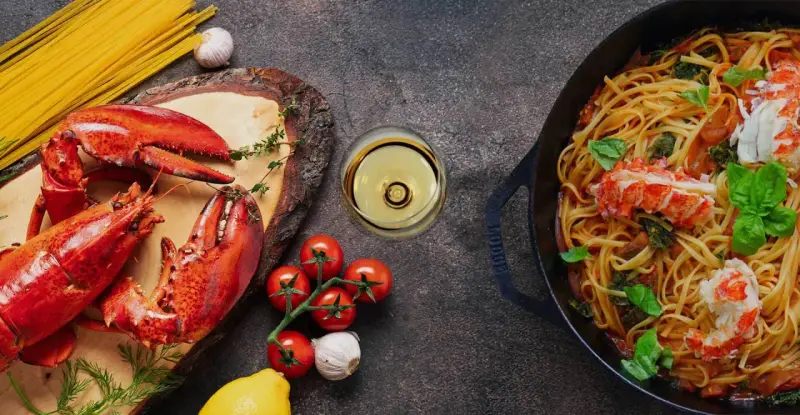 Pyszne spaghetti z homarem, świeże pomidory, czosnek i kieliszek chardonnay wino. Idealna kolacja.